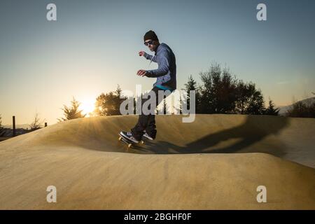 Skateboarder trainieren auf einem Pumptrack Park an einem sonnigen Sommertag. Stockfoto