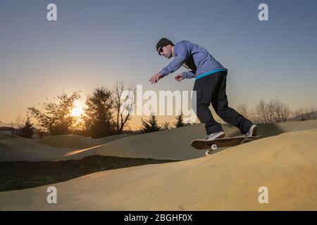 Skateboarder trainieren auf einem Pumptrack Park an einem sonnigen Sommertag. Stockfoto