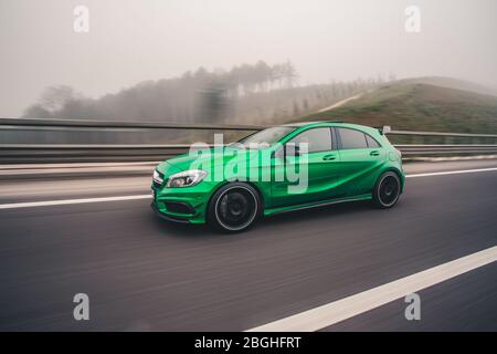 Grüner Mini-Sportwagen, der bei regnerischem Nebel über das Hochland fährt Stockfoto