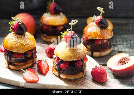 Süße Burger mit Brioche-Brötchen, Schokobrownie-Schicht, frischen Erdbeeren und geschmolzener Schokoladensauce. Stockfoto