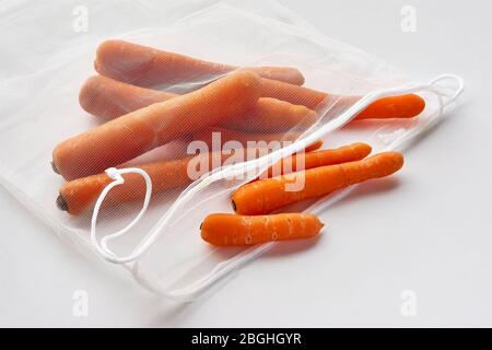 Orange Karotten in nachhaltiger Lebensmittelmaschentasche. Gemüse in wiederverwendbarer umweltfreundlicher Verpackung auf leichtem Hintergrund. Zero Waste Shopping Konzept. Stockfoto