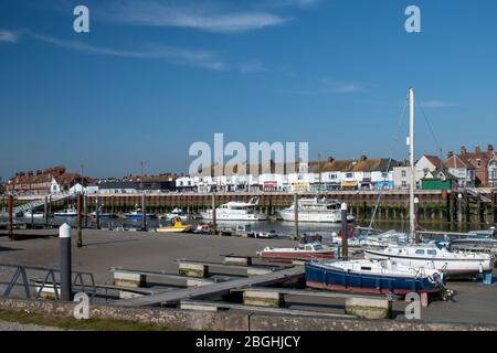 Littlehampton, West Sussex, Großbritannien, 21. April 2020. Der Fluss Arun vom Westufer aus gesehen, mit Segelbooten im Vordergrund und Geschäften von Littlehampton. Stockfoto