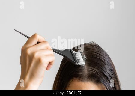 Closeup Frau Hände färben Haar mit einem schwarzen Pinsel. Färbung von weißem Haar zu Hause. Stockfoto