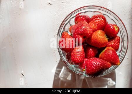 Erdbeeren in einer Glasschüssel. Aromatische Früchte. Gesundes Dessert. Heller Hintergrund. Stockfoto