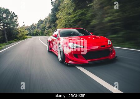 Superpower Red Rennwagen auf der Landschaft fahren durch Regenwälder, Vorderansicht Stockfoto