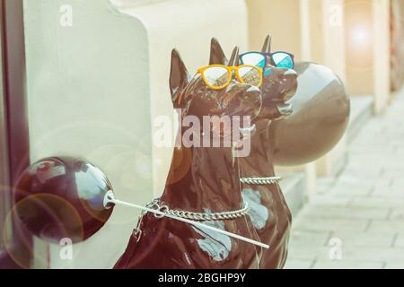 Schwarze Hundefiguren. Lustige große Hunde in leuchtend blauen und gelben Gläsern und Sonnenblendung. Foto mit Ton Stockfoto