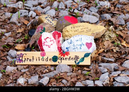 Felsen, die mit ermutigenden Worten, Herzen, Blumen und der kanadischen Maple Leaf Flag gemalt wurden, arrangiert von unbekannten Menschen in der Innenstadt von Toronto in der Nähe eines Eingangs zum Moore Park Ravine Trail während des Covid-19 Roman Coronavirus Ausbruch. Fotografiert am 20. April 2020 Stockfoto