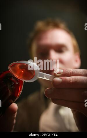 Mann gießt Hustenmischung auf einen Plastiklöffel Stockfoto