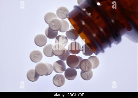Aspirin-Tabletten, die aus einer offenen Flasche austreten Stockfoto