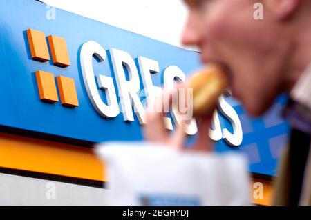 Ein Mann isst seine vor kurzem kaufen Greggs Essen. Stockfoto