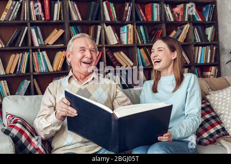 Vater und Tochter zu Hause Bibliothek sitzen halten Album lachen fröhlich Stockfoto