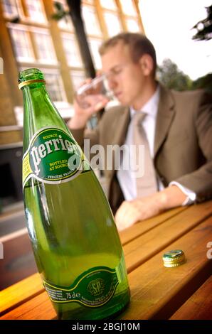 ein Mann genießt ein Glas Mineralwasser Perrier Wasser; eine Marke von Nestlé Waters. Stockfoto