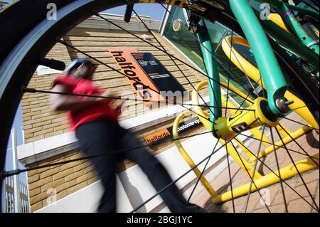 Ein Radfahrer zu Fuß zu seinem Fahrrad außerhalb eines Ladens Halfords. Stockfoto