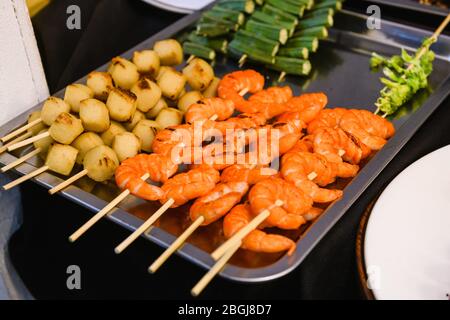 Gegrillte Meeresfrüchte auf Holzspieße aus nächster Nähe. Asiatische thai Street Sea Food Market Theke mit gegrillten gerösteten Shimps. Stockfoto