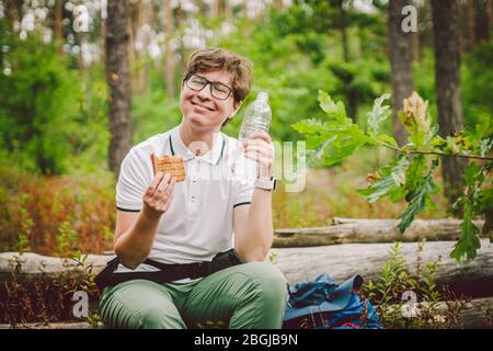 Frau, die Mittagessen nimmt eine Pause Wandern. Wanderer essen Sandwiches in der Natur. Touristen hielten zum Abendessen in der Waldgegend an. Pause Zum Mittagessen Stockfoto