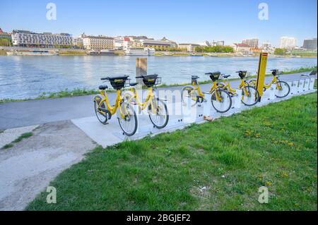 BRATISLAVA (SLOWAKEI) – APRIL 20 2020: Gelbe öffentliche Fahrräder in der Andockstation am Donauufer gesperrt - Bike-sharing Stockfoto