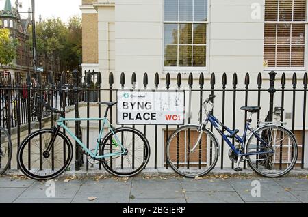 Zwei Fahrräder an die Geländer in Byng Place mit Straßenschild, London Bloomsbury WC1 Stockfoto