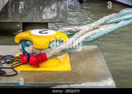 Ein mit Festmacherseilen umschwirnter Ankerplatz. Vor Anker lieg Schiffe am Hafenquai Stockfoto