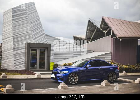 Blaue Sportlimousine vor einem futuristischen Gebäude geparkt Stockfoto