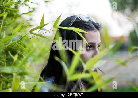 Junges Mädchen seitlich schauen geradeaus von Bambusblättern umgeben Stockfoto