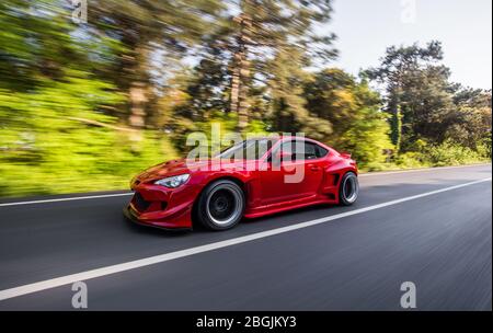 Superpower roten Rennwagen auf der Landschaft fahren durch Regenwälder, Winkel Ansicht Stockfoto