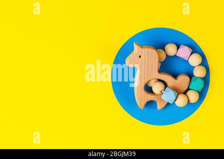 Baby Kind pädagogische natürliche Öko Null Abfall Holz Rassel Spielzeug auf gelbem und blauem Hintergrund Stockfoto