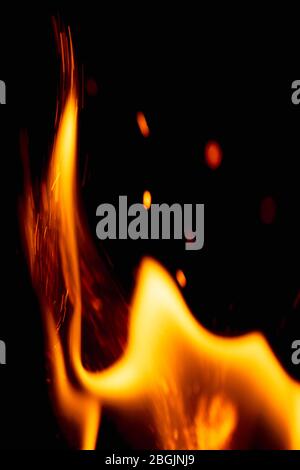 Kraftvolle brennende Flamme auf schwarzem Hintergrund. Helle Funken aus dem Feuer. Stockfoto