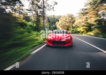 Superpower roten Rennwagen auf der Waldstraße Stockfoto