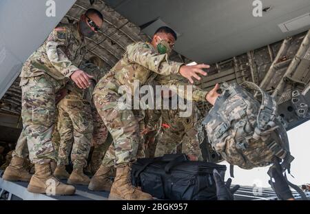 Mitglieder der Hawaii Nationalgarde laden ihre Ausrüstung auf die C-17, vom 204. Luftlift-Geschwader, Hawaii Air National Guard, die mehrere Truppenläufe nach Maui, Kauai und Hawaii machte, um bei der COVID-19-Reaktion zu helfen, 15. April 2020, Kalaeloa, Hawaii. In der vergangenen Woche wurden weitere 800 Mitglieder der Nationalgarde von Hawaii aktiviert, um allen Landkreisen weitere Unterstützung zu bieten. (FOTO der US Army National Guard von Sgt. John Schoebel) Stockfoto