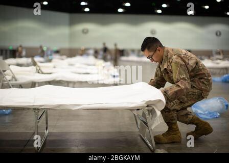 U.S. Air Force Tech. Sgt. Mario Lopez-Casas, ein Spezialist für Heizung, Belüftung, Klimaanlage und Kühlung mit der 146. Staffel von Civil Engineer in der 146. Luftbrücke der California Air National Guard, legt beim Einrichten einer Bundesärztestation Bettlaken auf ein Krankenhausbett, 29. März 2020, Innerhalb des Los Angeles Convention Center als Teil der landesweiten COVID-19-Reaktionsbemühungen Kaliforniens. Dies ist die dritte medizinische Station, die der Airmen im Staat eingerichtet hat. (USA Video der Air National Guard von Sgt. Crystal Housman) Stockfoto