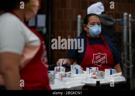 Chelsea, Massachusetts, USA. April 2020. Freiwillige geben warme Mahlzeiten weg. Die COVID-19, Corona Virus, Situation in Chelsea, Massachusetts ist ein wichtiger Hotspot. Chelsea ist die am stärksten getroffenen Städte im Bundesstaat. Chelsea ist eine lateinamerikanische Einwandererbevölkerung mit 80% der Bevölkerung sind wichtige Arbeitskräfte, wie Lebensmittelarbeiter. Mit verlorenen Jobs haben Leute eine harte Zeit, in der Lage zu sein, Nahrung zu erhalten. Die Heilsarmee gibt täglich Lebensmittelboxen und warme Mahlzeiten aus. Kredit: Allison Dinner/ZUMA Wire/Alamy Live News Stockfoto