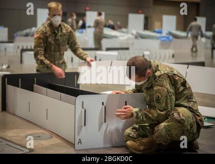 Soldaten des 1-102. Infanterie-Regiments bauen ein Feldlazarett im Connecticut Convention Center in Hartford, Connecticut, 11. April 2020. Soldaten und Luftwaffe der Connecticut National Guard stellen am Standort über 600 Betten als potenzielle Überspannungskapazität für Patienten auf, die sich von COVID-19 erholen. (USA Foto der Air National Guard von Staff Sgt. Steven Tucker) Stockfoto