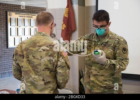 U.S. Army PFC. Robert Ardis, 251st Area Support Medical Company Health Care Specialist, nimmt die Temperatur eines US Army National Guard Soldier, der als Teil der Joint Task Force 59, South Carolina National Guard, für den aktiven Dienst des Staates während eines medizinischen Vorscreenings am 1. April 2020 in Laurens, South Carolina zur Unterstützung der staatlichen COVID-19-Maßnahmen. Das medizinische Vorscreening ist Teil der Maßnahmen, die ergriffen werden, um die Exposition von COVID-19 für die Dienstmitglieder zu begrenzen und die Gesundheit der Truppe zu schützen. Die South Carolina National Guard ist weiterhin bereit, die Grafschaften zu unterstützen Stockfoto