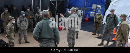 Mitglieder des 107. Angriffs-Wing-Teams für die Suche und Wiederherstellung von Todesfällen der New York Air National Guard hören sich am 4. April 2020 eine morgendliche Einweisung vor dem Bellevue Hospital in New York City an. Die Airmen unterstützen das Büro des Chefinalexaminers von New York City als Teil der Reaktion des Staates New York auf die COVID 19-Pandemie. Sie werden auf die würdige Wiederherstellung menschlicher Überreste geschult. (USA Foto der Air National Guard von Senior Airman Sean Madden) Stockfoto