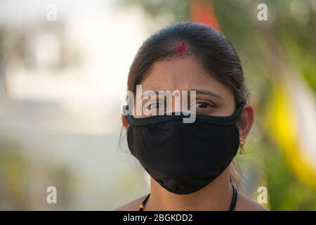 Detail der indischen Frau trägt eine schwarze Gesichtsmaske. Frontansicht, unscharfer Hintergrund. Corona-Virus, COVID-19-Quarantäne. Maske als Schutz. Stockfoto