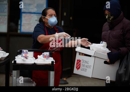 Chelsea, Massachusetts, USA. April 2020. Freiwillige geben warme Mahlzeiten weg. Die COVID-19, Corona Virus, Situation in Chelsea, Massachusetts ist ein wichtiger Hotspot. Chelsea ist die am stärksten getroffenen Städte im Bundesstaat. Chelsea ist eine lateinamerikanische Einwandererbevölkerung mit 80% der Bevölkerung sind wichtige Arbeitskräfte, wie Lebensmittelarbeiter. Mit verlorenen Jobs haben Leute eine harte Zeit, in der Lage zu sein, Nahrung zu erhalten. Die Heilsarmee gibt täglich Lebensmittelboxen und warme Mahlzeiten aus. Kredit: Allison Dinner/ZUMA Wire/Alamy Live News Stockfoto