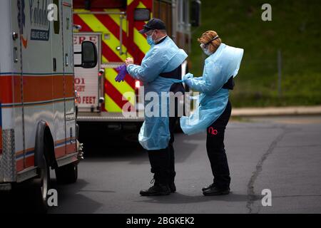 Chelsea, Massachusetts, USA. April 2020. Ärzte helfen sich gegenseitig, PSA zu tragen. Die COVID-19, Corona Virus, Situation in Chelsea, Massachusetts ist ein wichtiger Hotspot. Chelsea ist die am stärksten getroffenen Städte im Bundesstaat. Chelsea ist eine lateinamerikanische Einwandererbevölkerung mit 80% der Bevölkerung sind wichtige Arbeitskräfte, wie Lebensmittelarbeiter. Krankenwagen reagieren Tag und Nacht auf Anrufe, die sich auf das Virus beziehen. Sie haben einen Mangel an PSA und sind nicht immer in der Lage, angemessene Kleider und Schutzkleidung zu tragen. Kredit: Allison Dinner/ZUMA Wire/Alamy Live News Stockfoto