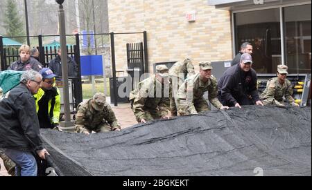 Soldaten der New Yorker Armee-Nationalgarde bewegen während der Platzierung von Zelten im New York-Presbyterian-Hudson Valley Hospital in Cortlandt Manor, NY, einen Boden, da medizinische Einrichtungen sich auf die Reaktion auf den Ausbruch von COVID 19 Patienten am 20. März 2020 vorbereiten. Die Soldaten sind Teil der landesweiten Bemühungen, Mitglieder der Nationalgarde zur Unterstützung der lokalen Behörden während der Pandemie einzusetzen. Foto der US Army National Guard von Oberst Richard Goldenberg. Stockfoto