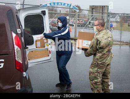 U.S. Army Sgt. Brian Dinse, 1-102. Infanterie-Regiment, lädt persönliche Schutzausrüstung in ein Fahrzeug bei der New Britain Armory in New Britain, Connecticut, 9. April 2020. Soldaten der Connecticut National Guard unterstützten das Connecticut Department of Public Health bei der Verteilung von Masken, Handschuhen und Gesichtsschutzschilden an lokale Pflegeheime als Reaktion auf die COVID-19-Pandemie. (USA Foto der Air National Guard von Staff Sgt. Steven Tucker) Stockfoto