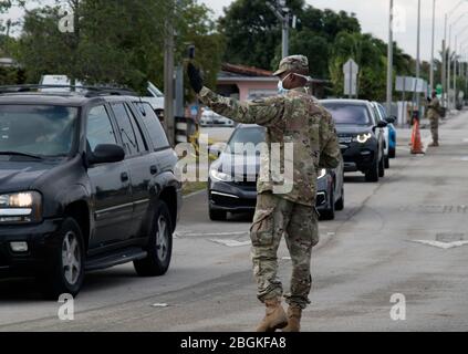 Ein Florida-Nationalgardisten-Soldat leitet ein Gemeindemitglied in den Ort am CBTS Amelia Earhart Park, Hialeah. Die Florida National Guard unterstützt Miami-Dade County bei der Prüfung der lokalen Gemeinschaft. (FOTO DER US Army von Sgt. Leia Tascarini) Stockfoto