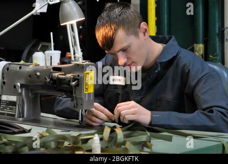 Soldaten der Oregon Army National Guard der Alliierten Handelsabteilung arbeiten hart daran, persönliche Schutzausrüstung (PSA) zu erstellen, um die Bedürfnisse der anderen Gardisten während des Ausbruchs der COVID-19 am 7. April 2020 im Lager Withycombe in Clackamas, Oregon, zu unterstützen. Die Teams arbeiten normalerweise an Reparaturteilen wie Sitzbezügen und Zelten, stellen aber 1,000 Masken und 1,000 Gesichtsschutzscheiben her, um die Verwendung von PSA aus dem nationalen Notvorrat zu vermeiden. (Foto der Nationalgarde von John Hughel, Oregon Military Department Public Affairs) Stockfoto