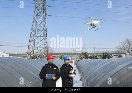 Zwei Mitarbeiter steuern eine Drohne, um elektrische Leitungen zu untersuchen, um die Sicherheit der Stromversorgung Beijing-Shanghai Hochgeschwindigkeitsbahn, Yaopujing Stadt, Na zu gewährleisten Stockfoto