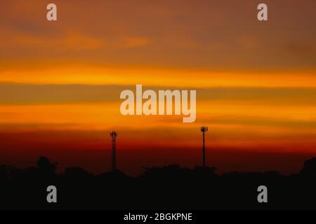 Silhouette von schönen Sonnenuntergang mit Fernsehantenne oder Telekommunikation Türme haben eine Menge von verschiedenen Antennen, Orange Himmel mit Sonne und Wolken. Stockfoto