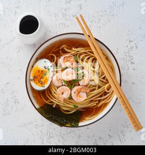 Asiatische Suppe mit Nudeln, Ramen mit Garnelen, Miso Paste, Sojasoße. Weißer Steintisch, Draufsicht Stockfoto