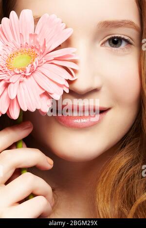 Ausdruck Nahaufnahme Porträt von schönen gesunden lächelnden Rotschopf Teenager-Mädchen mit Gerbera Blume Stockfoto