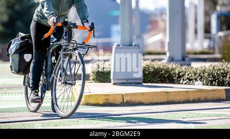 Ein Mann auf einem Fahrrad Pedale ein Fahrrad überquert Straßenbahnschienen auf einer dedizierten Kreuzung für Radfahrer und Fußgänger bevorzugen gesunde Lebensweise mit Radfahren r Stockfoto