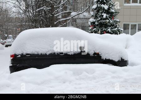 Auto auf einer Straße in der Stadt im Winter mit Schnee bedeckt. Stockfoto