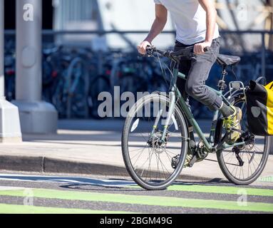 Ein Mann auf einem Fahrrad Pedale ein Fahrrad überquert Straßenbahnschienen auf einer dedizierten Kreuzung für Radfahrer und Fußgänger bevorzugen gesunde Lebensweise mit Radfahren r Stockfoto