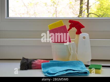 Behälter mit Reinigungsartikeln vor dem Fenster Stockfoto