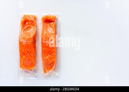 Roter Fisch oder Lachsfilets in Vakuumverpackung auf weißem Hintergrund. Frische Fisch-, Zitronen- und Dill-Kochzutaten. Omega-3 Stockfoto